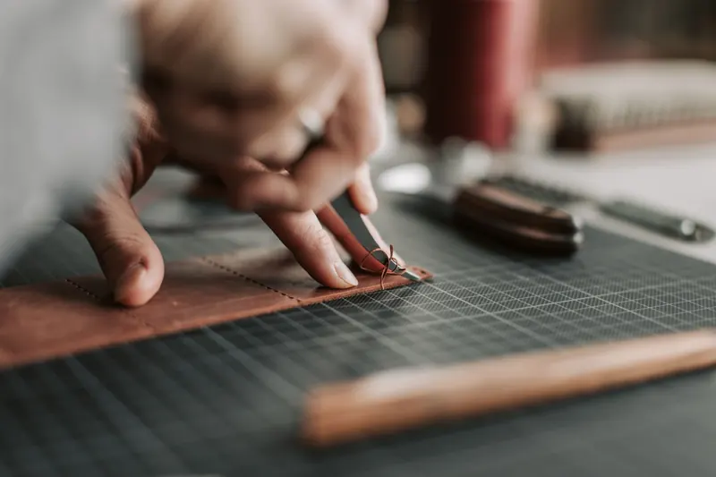 Hands cutting brown leather on a mat