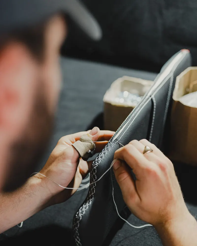 Hands stitching a leather seat cover